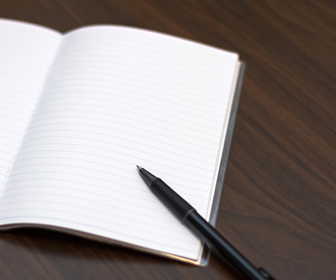 開いたノートとボールペンの写真