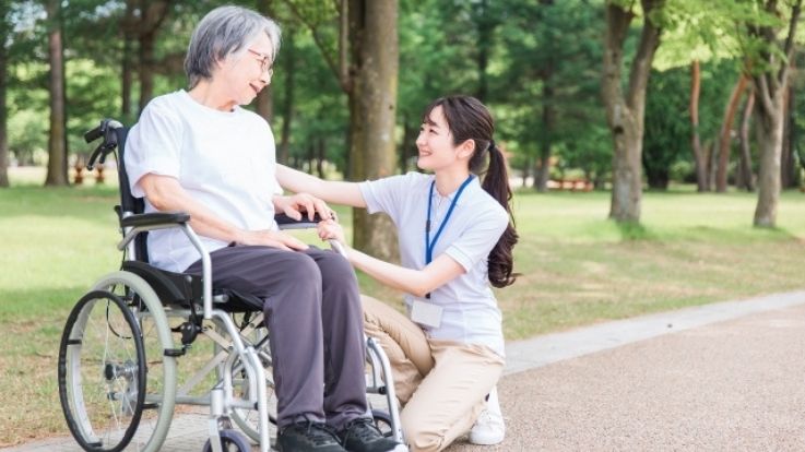 車椅子を使う方と介護職員の画像